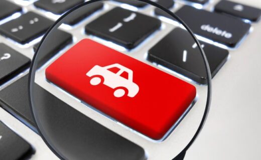 Tecla vermelha com ícone de carro sob uma lupa em um teclado de computador
