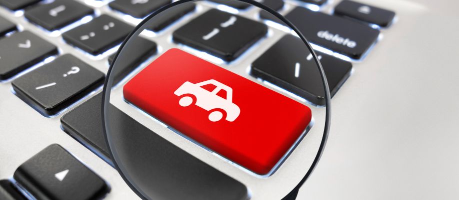 Tecla vermelha com ícone de carro sob uma lupa em um teclado de computador