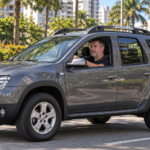Homem dirigindo SUV cinza visto de lado, com motorista visível pela janela