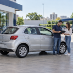 Compradores conferem documentos de um carro usado ao lado do veículo em uma loja